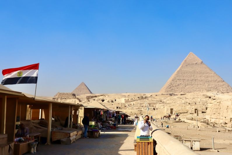 Geopolitical Factors - a woman taking a picture of the pyramids in egypt