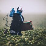 Labor Shortages - man in blue jacket wearing white helmet standing on green grass field during daytime