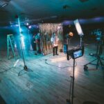 Production Capacities - man standing in front of cameras with string lights background