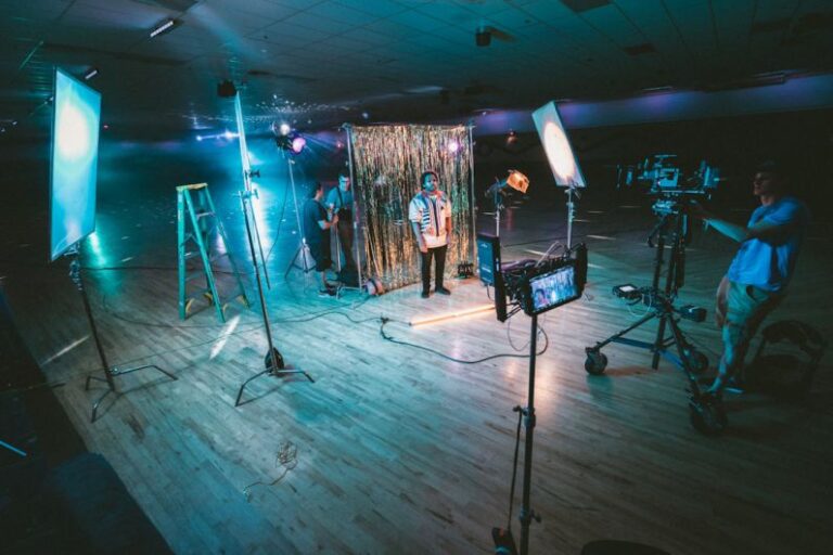 Production Capacities - man standing in front of cameras with string lights background