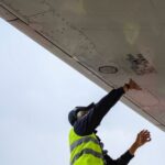 Maintenance Pitfalls - man in green safety vest standing under white structure