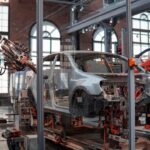 Smart Factory - gray vehicle being fixed inside factory using robot machines