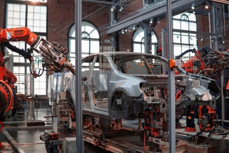 Smart Factory - gray vehicle being fixed inside factory using robot machines