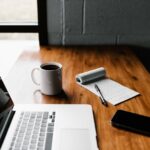 Maintenance Schedule - MacBook Pro, white ceramic mug,and black smartphone on table