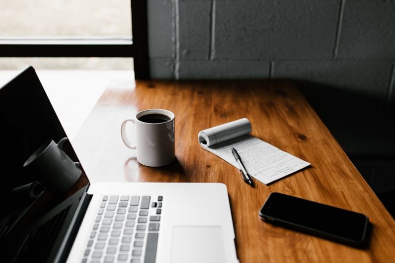 Maintenance Schedule - MacBook Pro, white ceramic mug,and black smartphone on table