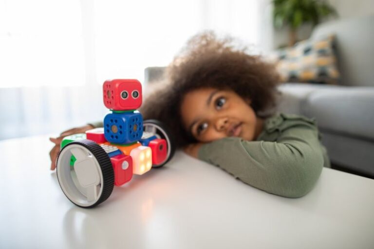Precision Robotics - boy lying on bed playing with red and blue toy truck